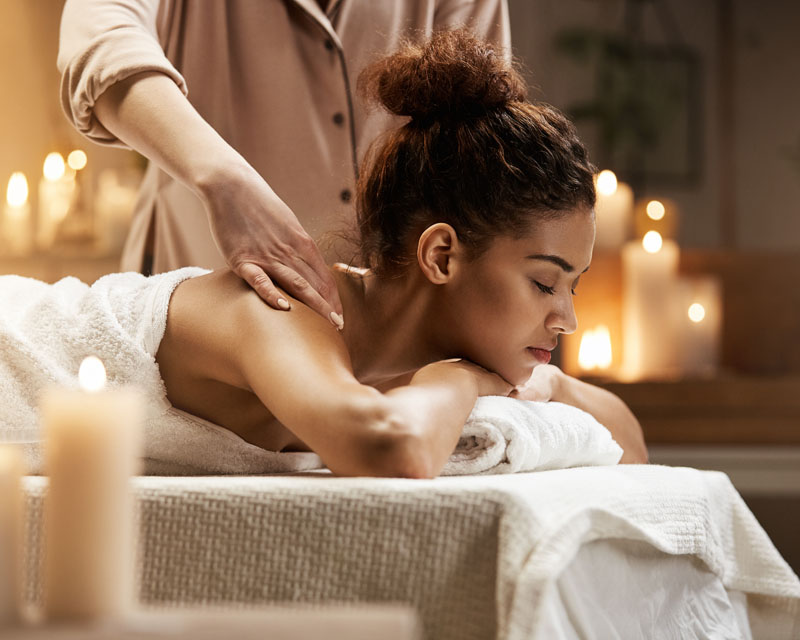 Tender african girl smiling enjoying massage with closed eyes in spa resort.